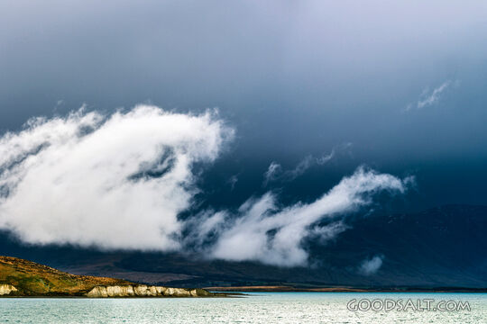 Heavy dark sky behind yellow clay cliffs.