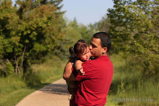 Man comforting crying little girl outdoors.